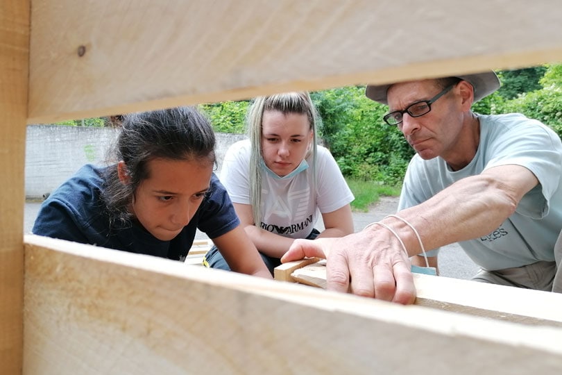 Gruppenfreiwilligendienst: zwei junge Frauen arbeiten unter Anleitung mit Holz